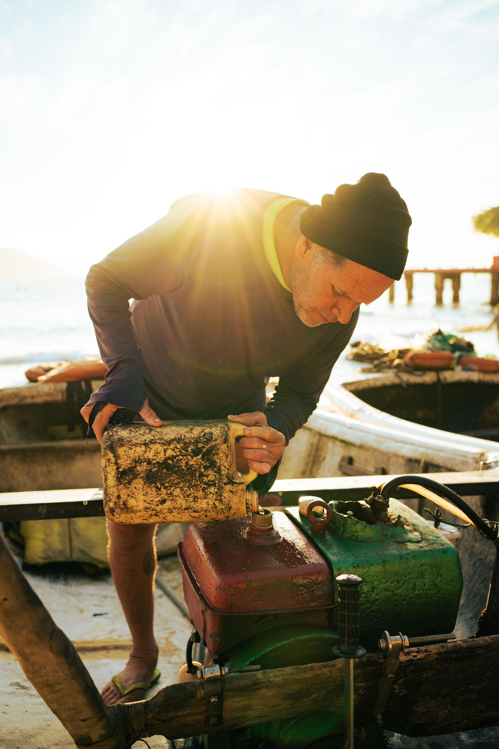 Person repairing a small boat engine near the shore